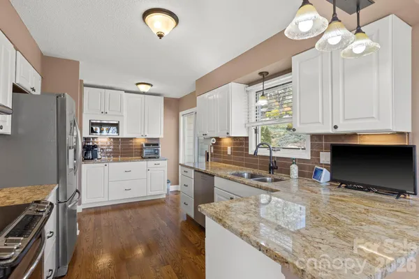 a kitchen with stainless steel appliances granite countertop a sink refrigerator stove and microwave