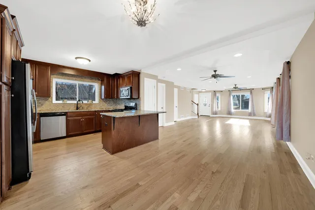 a living room with stainless steel appliances kitchen island granite countertop wooden floors and view living room