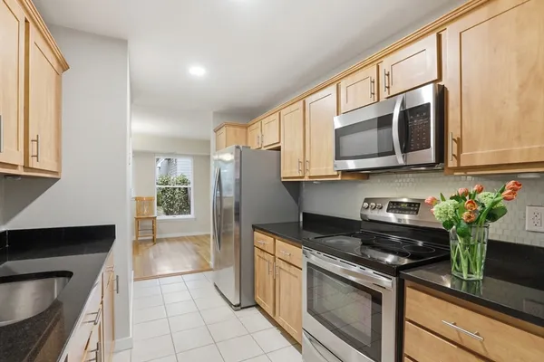 a kitchen with stainless steel appliances granite countertop a sink a stove a microwave a refrigerator and cabinets