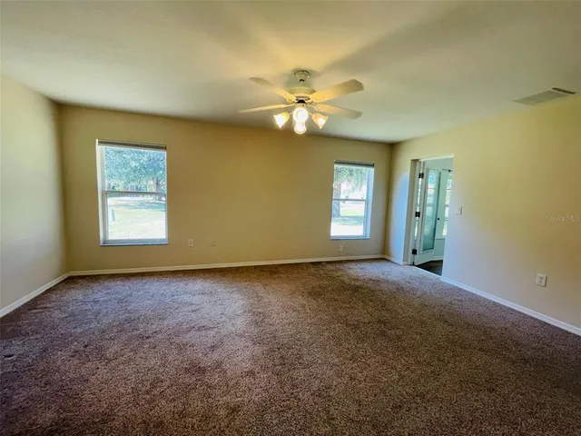 a view of a big room with windows and chandelier fan