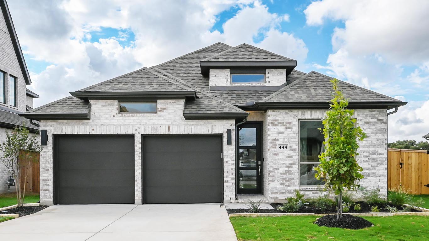 French country inspired facade with a shingled roof, concrete driveway, and an attached garage
