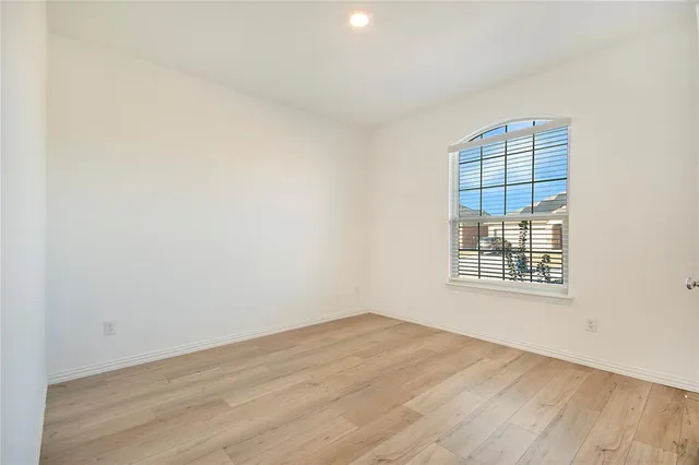 a view of a room that has wooden floor and a window