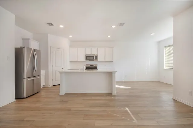 a view of kitchen with refrigerator microwave and cabinets