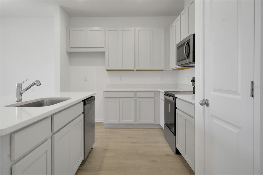 2824 Doolittle Street Tavares, FL 32778 - Photo 18 of 32 a kitchen with white cabinets appliances and sink