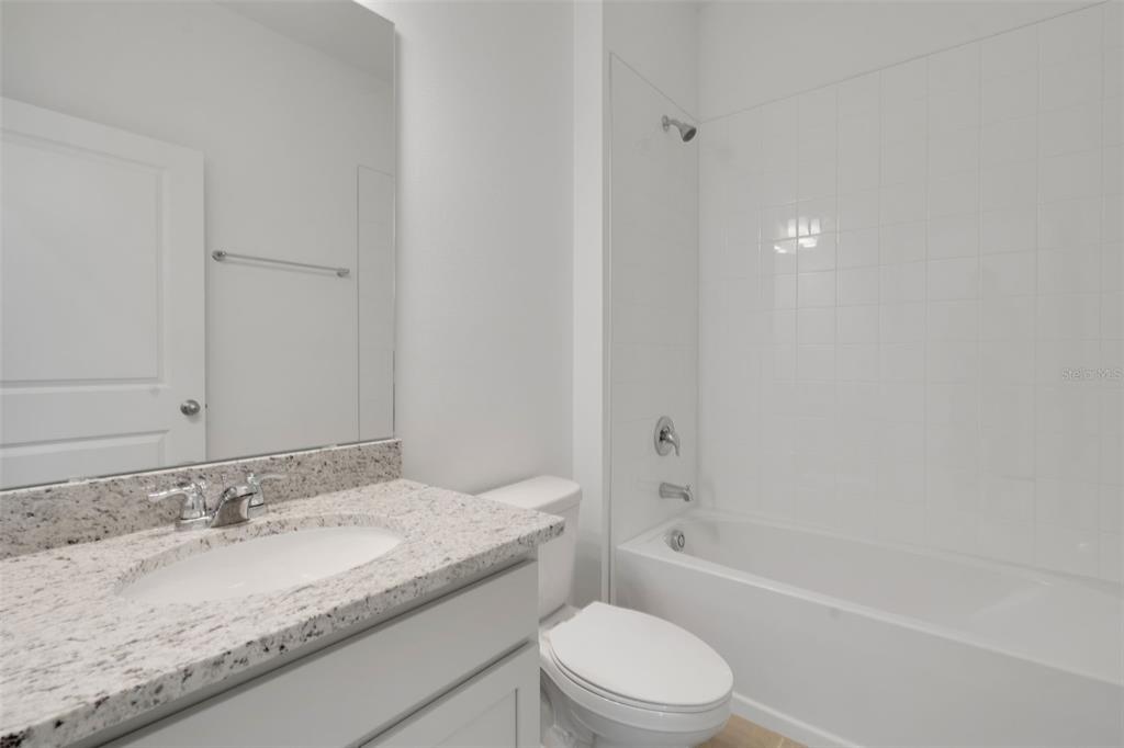 2824 Doolittle Street Tavares, FL 32778 - Photo 27 of 32 a bathroom with a granite countertop sink a toilet and bathtub