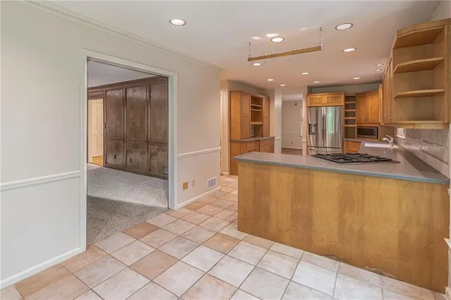 a view of kitchen with granite countertop cabinets and refrigerator