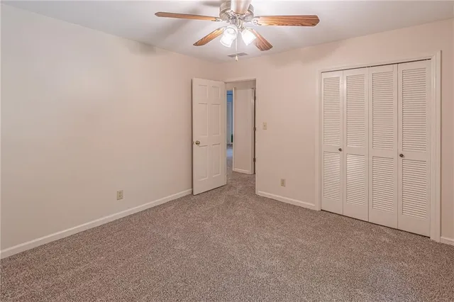 an empty room with closet and a chandelier fan