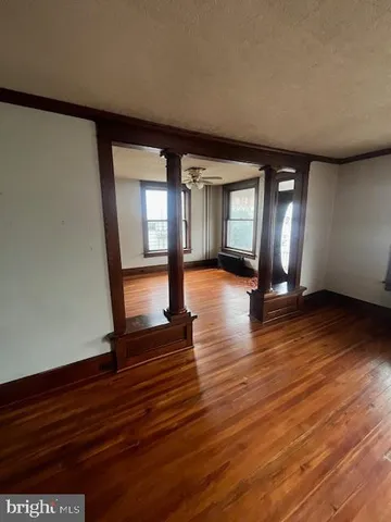 a view of an empty room with window and wooden floor