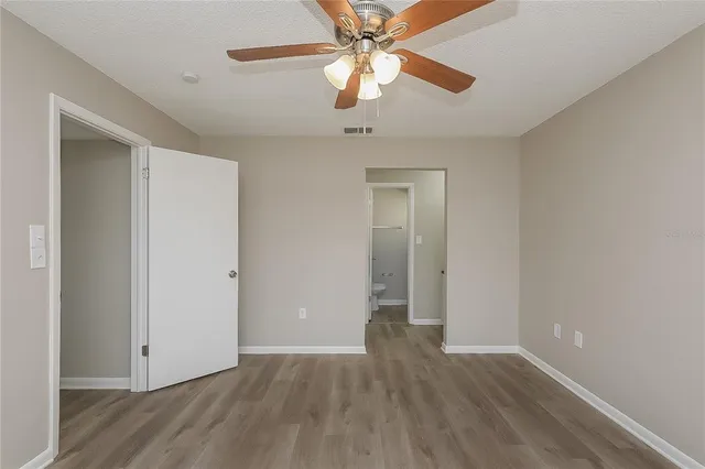 an empty room with wooden floor chandelier fan and closet area