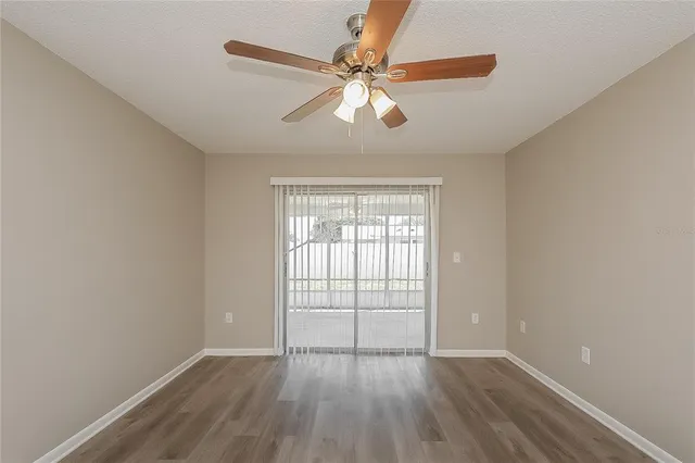 an empty room with wooden floor fan and windows