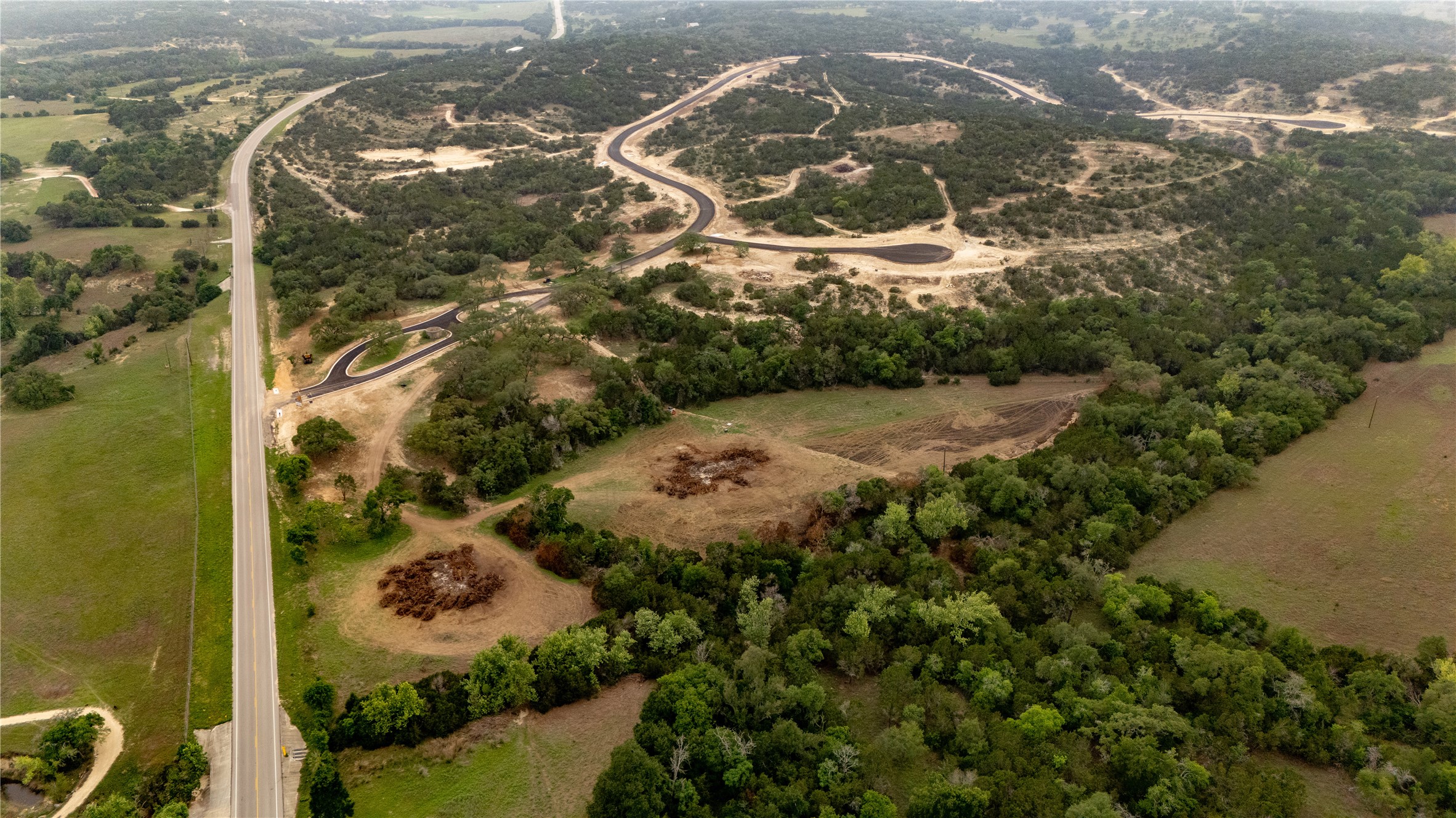 Lot 26 Ranch Road 165 Dripping Springs, TX 78620 - Photo 8 of 13 Expansive undeveloped land featuring a paved road, natural tree coverage, and cleared areas