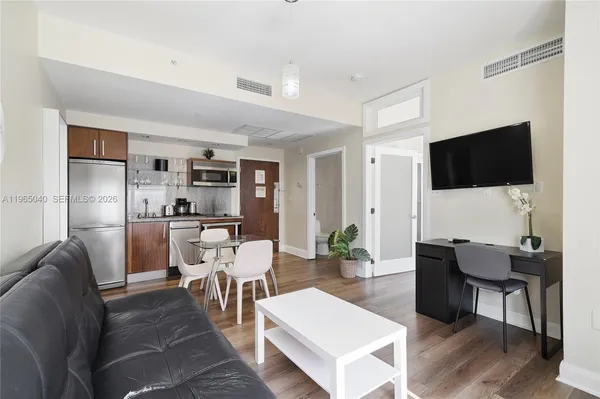 a living room with furniture a flat screen tv and kitchen view