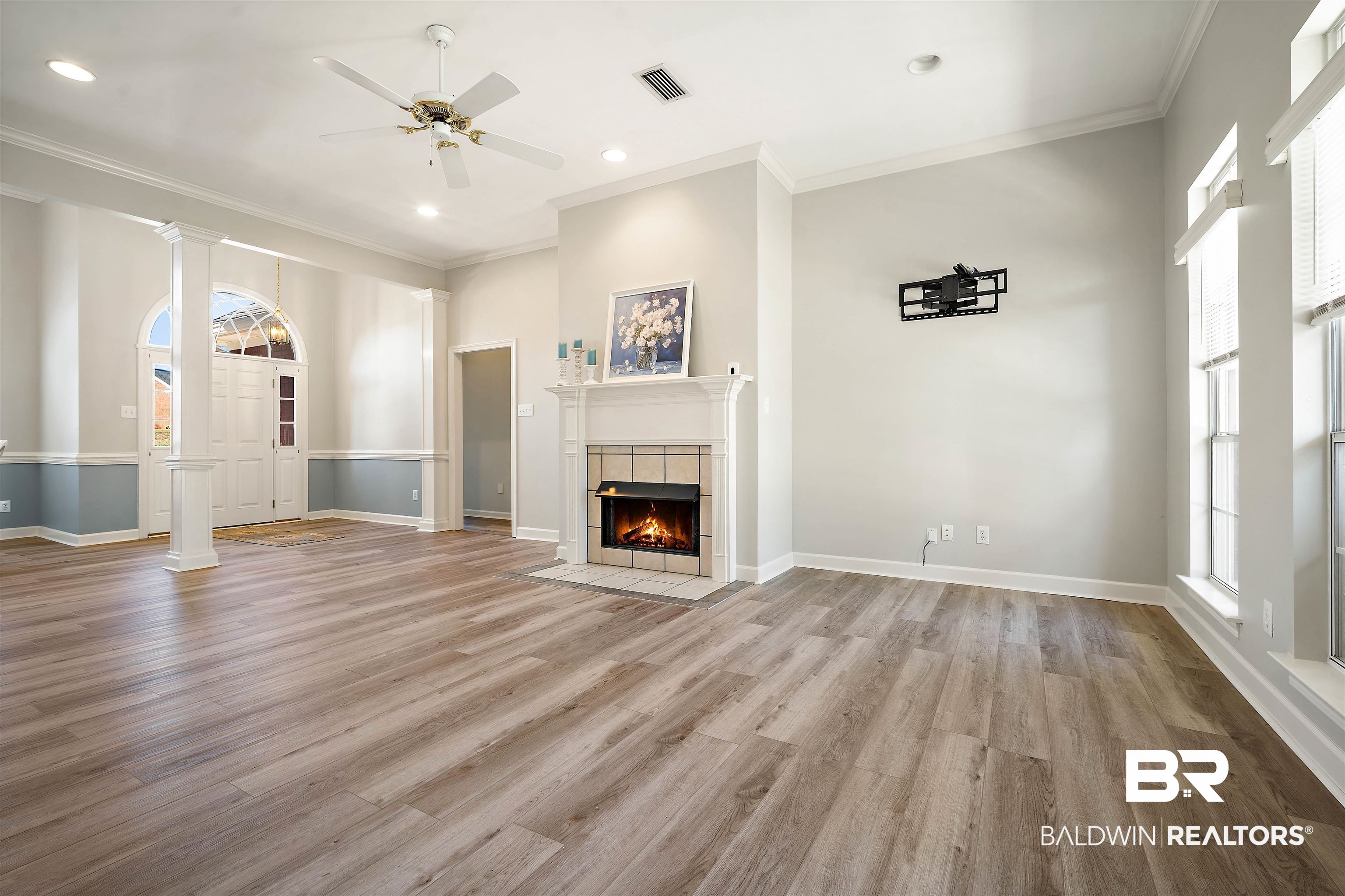 615 Summerlake Place Mobile, AL 36608 - Photo 5 of 35 Unfurnished living room with light wood-style flooring, ornamental molding, a ceiling fan, ornate columns, and a tiled fireplace