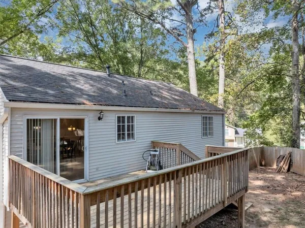 a view of a wooden house and a yard with large trees