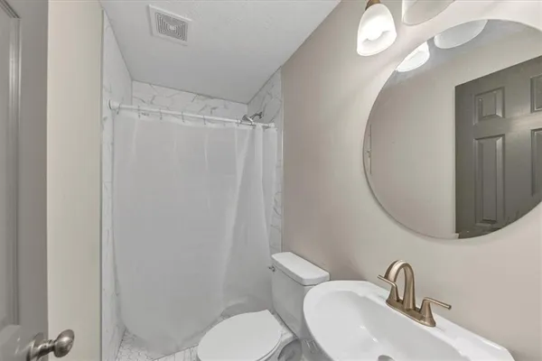a bathroom with a toilet sink vanity and mirror