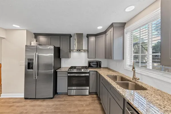 a kitchen with granite countertop a sink stove and refrigerator