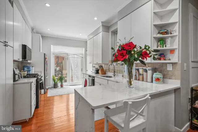 a kitchen with a refrigerator a sink dishwasher and a dining table with wooden floor
