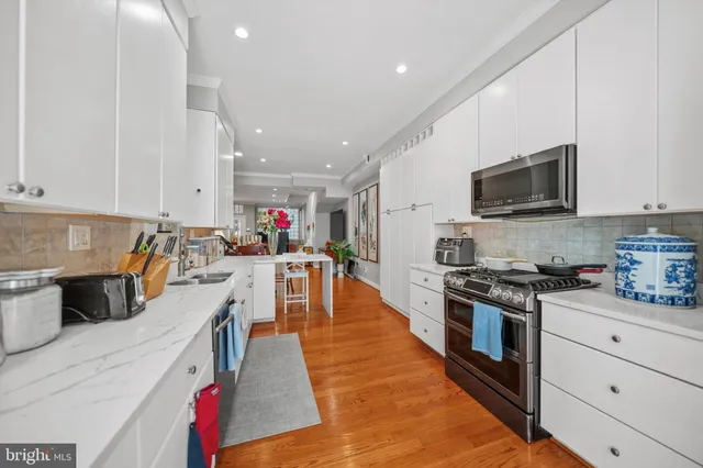 a large kitchen with stainless steel appliances granite countertop a stove a sink dishwasher and a microwave with wooden floor