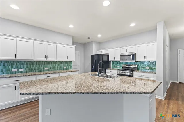 a kitchen with granite countertop a sink and a stove top oven