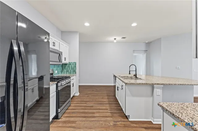 a kitchen with granite countertop a sink stove and refrigerator