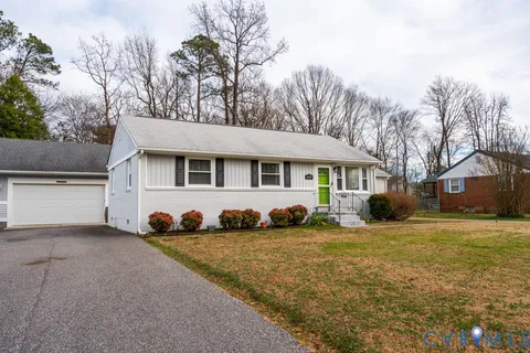 a front view of a house with a garden and trees