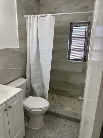 a white toilet sitting next to a shower curtain