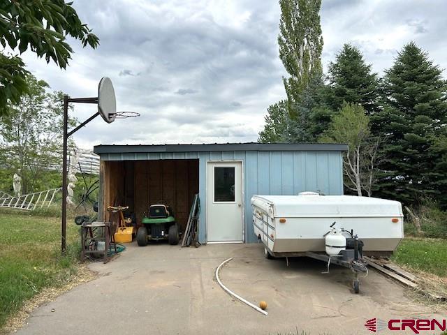 39389 Pitkin Road Paonia, CO 81428 - Photo 21 of 42 covered storage, shelving inside and a backetball goal with a concrete area