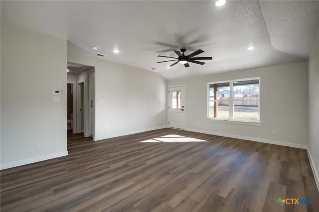 a view of an empty room with a window and wooden floor