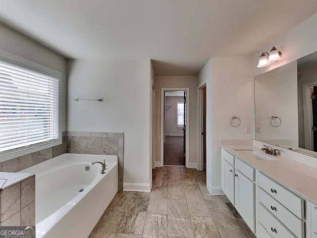 a spacious bathroom with a tub double vanity sink a mirror and a shower