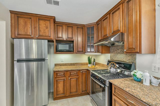a kitchen with stainless steel appliances granite countertop a refrigerator sink and stove