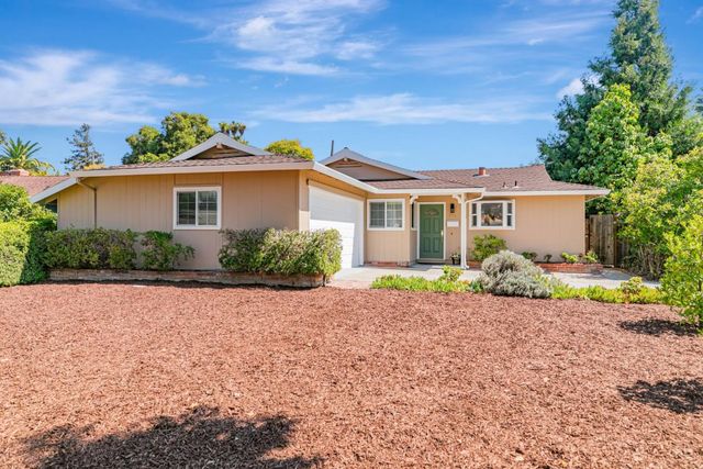 a front view of a house with a yard and potted plants