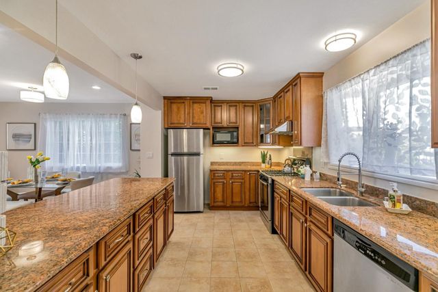 a kitchen with stainless steel appliances granite countertop a sink a stove and a refrigerator
