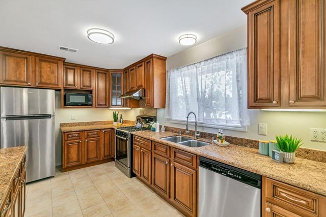 a kitchen with stainless steel appliances granite countertop a sink a stove and a refrigerator