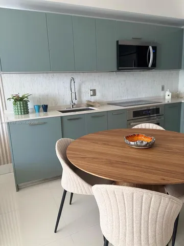 a kitchen with a table chairs microwave and cabinets