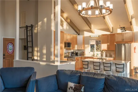 a dining room with wooden floor a chandelier a glass table and chairs