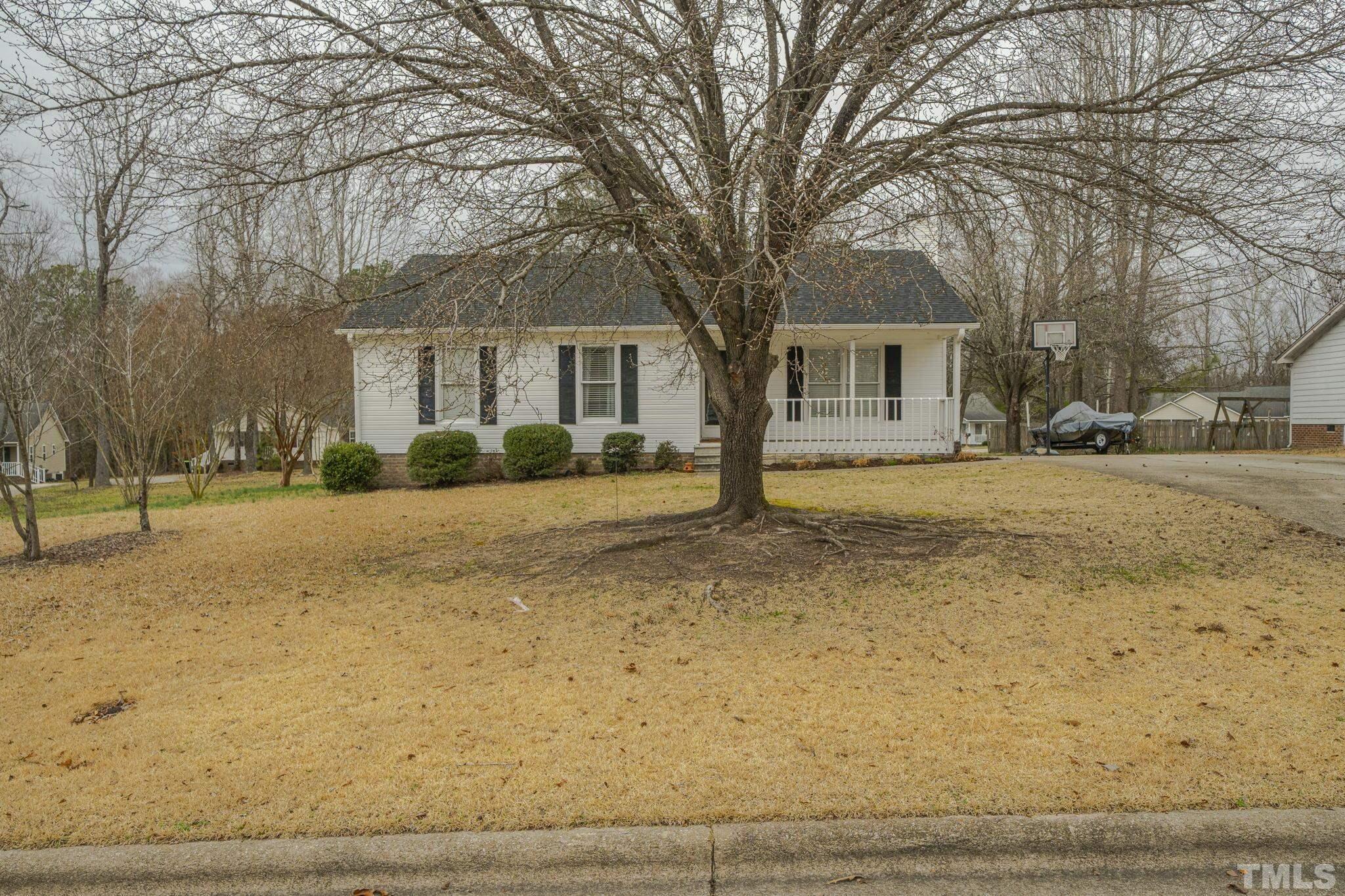 a front view of a house with a yard covered with snow and trees