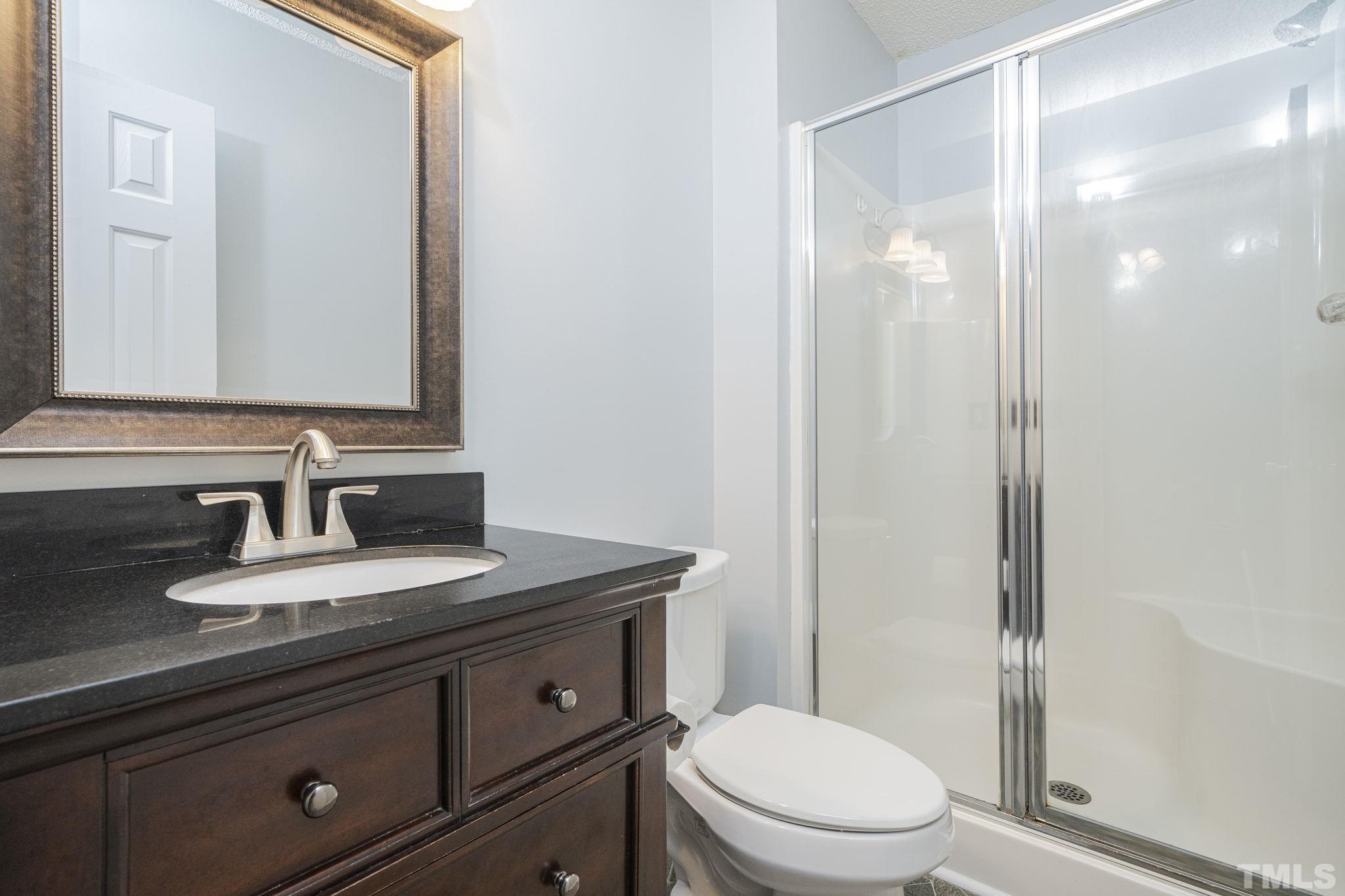 105 Pineview Drive Zebulon, NC 27597 - Photo 18 of 29 a bathroom with a granite countertop sink a toilet and a mirror