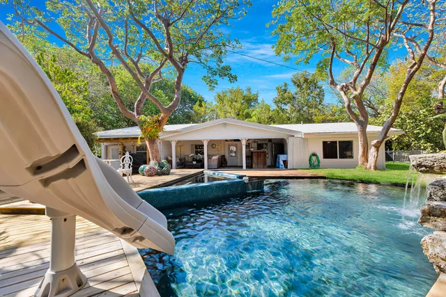 an aerial view of residential house with outdoor space and trees all around