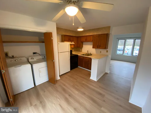 a kitchen with stainless steel appliances granite countertop a refrigerator a sink dishwasher a stove and white countertops with wooden floor