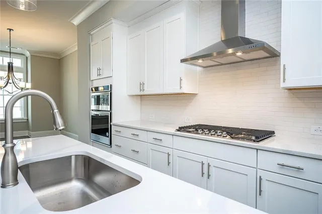an empty room with wooden floor ceiling fan and kitchen view