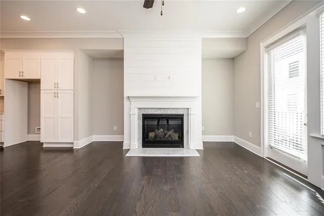 a view of a room with wooden floor a ceiling fan and kitchen view