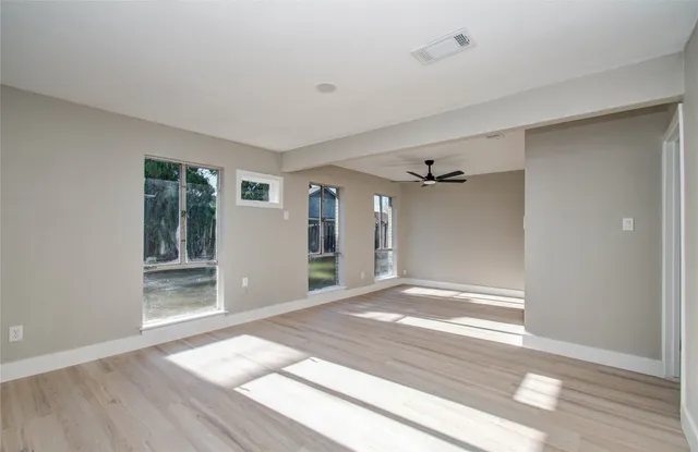 a view of an empty room with wooden floor and a window