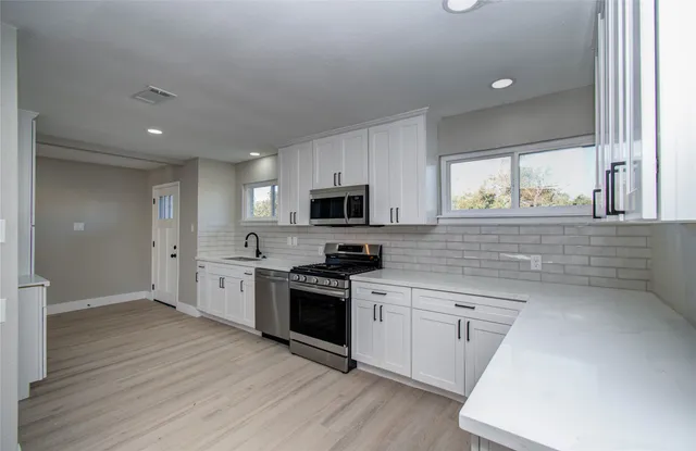 a kitchen with stainless steel appliances granite countertop a stove a sink and a microwave