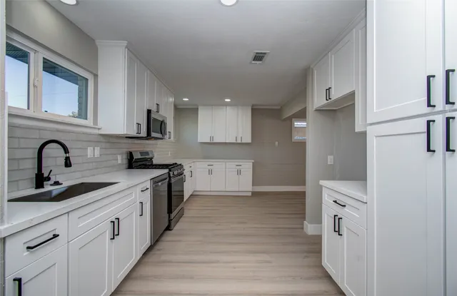 a kitchen with white cabinets and appliances
