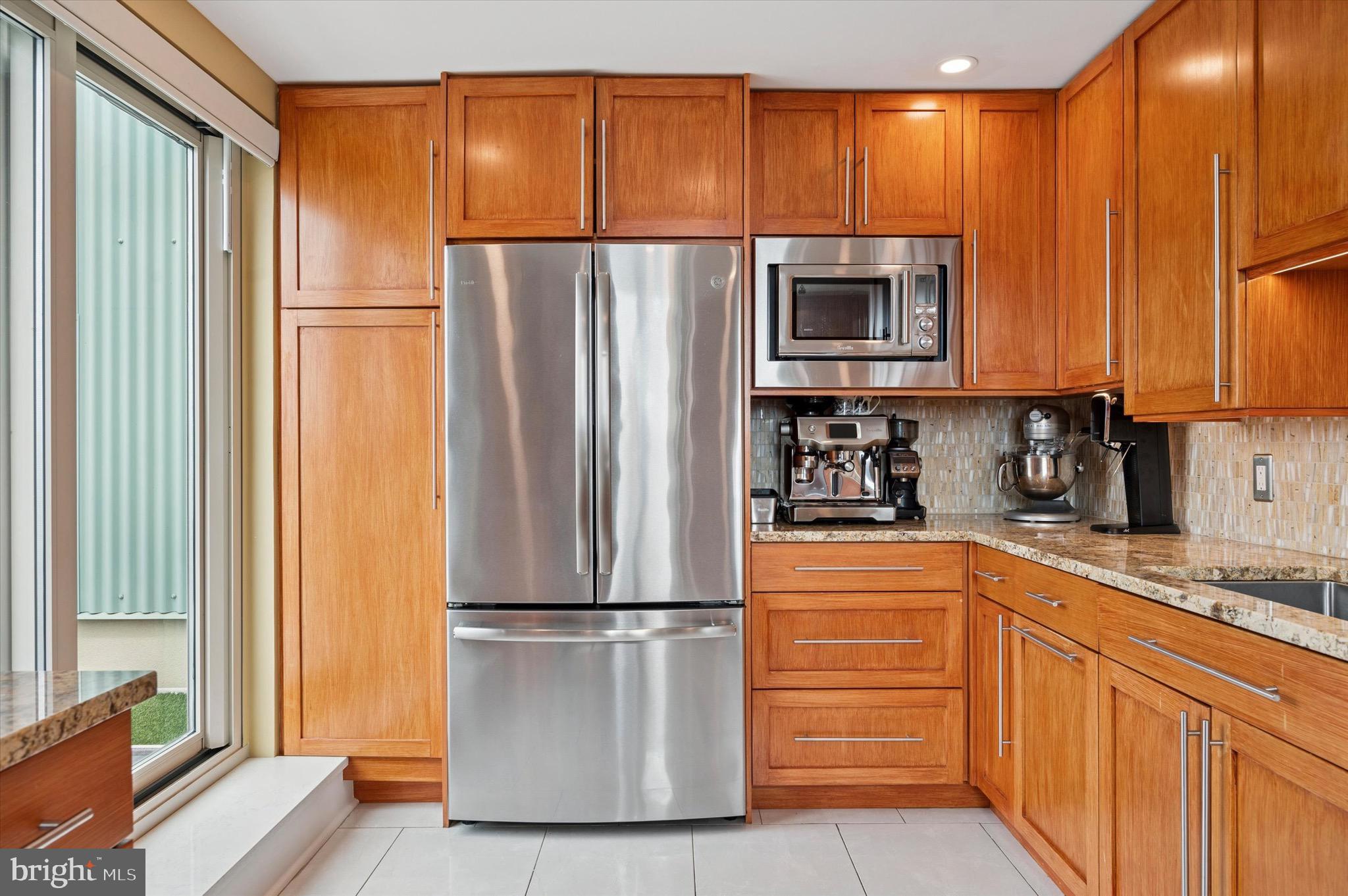 717 South Christopher Columbus Boulevard, Unit 802 Philadelphia, PA 19147 - Photo 10 of 32 a kitchen with stainless steel appliances granite countertop a refrigerator a stove and a sink with wooden cabinets