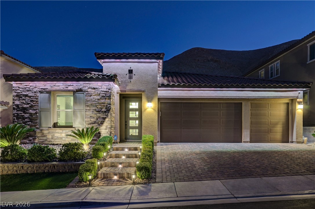 3943 Reyes Avenue Las Vegas, NV 89141 - Photo 90 of 95 Illuminated stone facade and paver driveway lead to this striking desert-contemporary home at twilight.