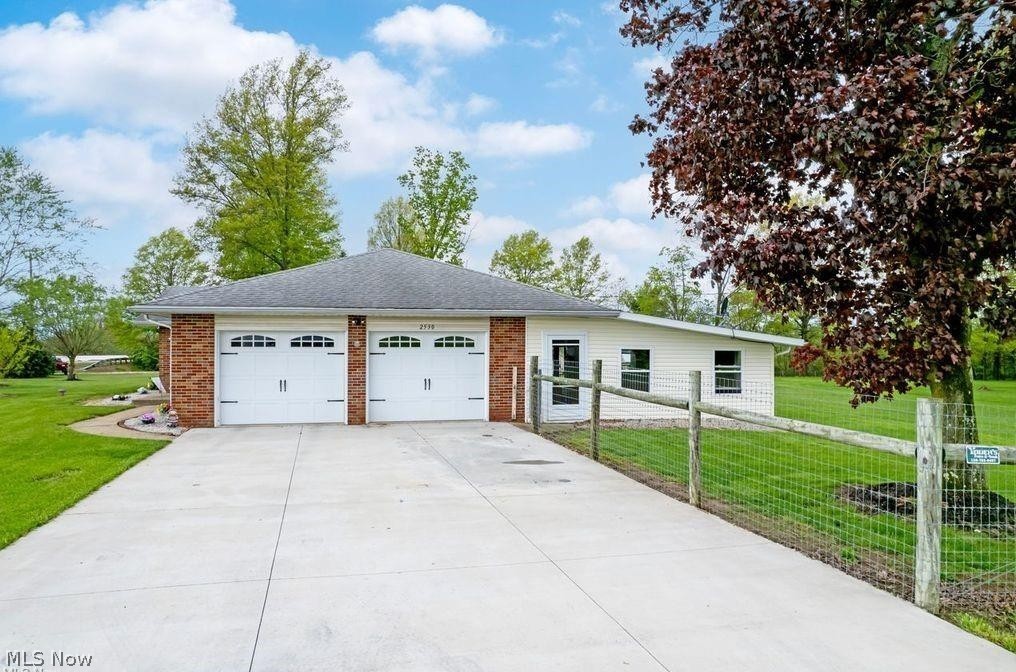2530 Tuckahoe Road Wooster, OH 44691 - Photo 7 of 29 Exterior featuring a two-car garage with white paneled doors, brick siding details, a grey shingle roof, and a concrete driveway