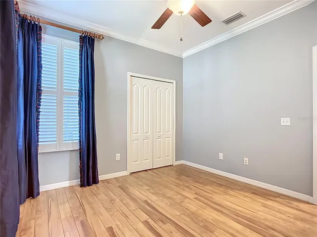 a view of empty room with wooden floor and fan