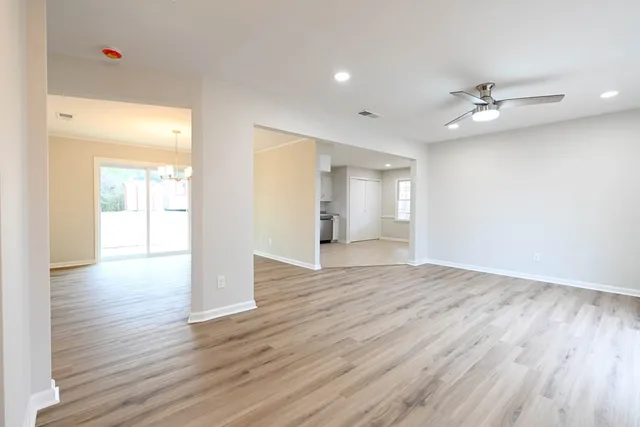 a view of an empty room with wooden floor and a ceiling fan