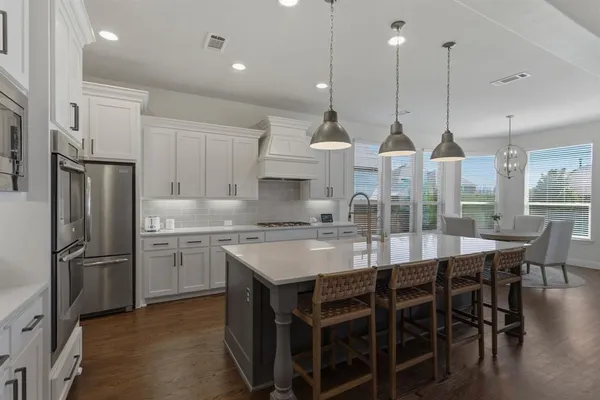 a kitchen with kitchen island granite countertop a table chairs stainless steel appliances and cabinets
